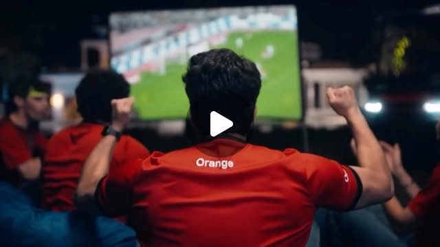 Fans in Orange shirts cheering at a match screening